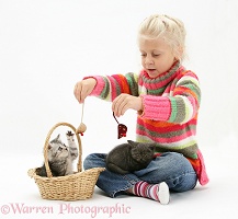 Girl playing with kittens in a basket