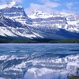 Rocky Mountains reflected in lake with ice