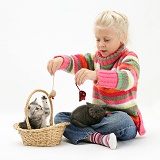 Girl playing with kittens in a basket