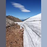 Rugged alpine landscape with snow and lenticular cloud