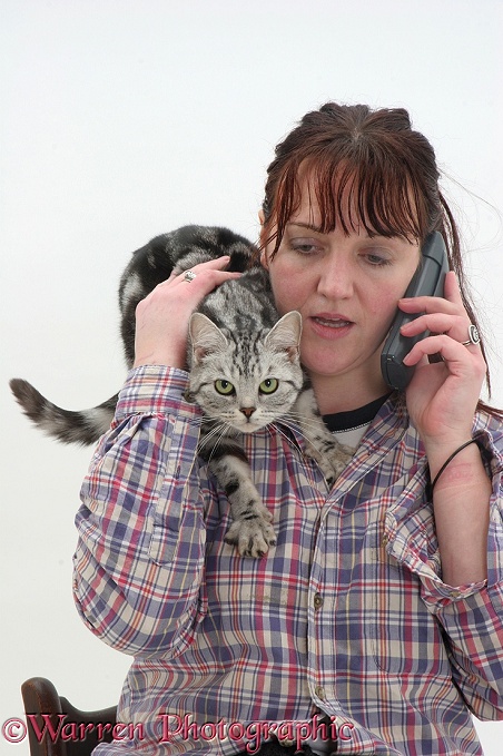 Woman phoning with cat on her shoulder, white background
