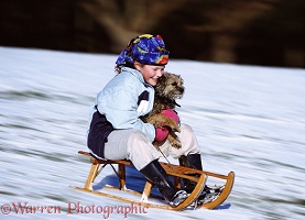 Girl tobogganing with a dog