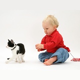 Toddler with black-and-white kitten and catnip mouse